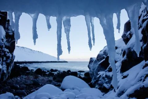 Art frame of white snow cold icicles on top foreground and stones beach Stock Photos