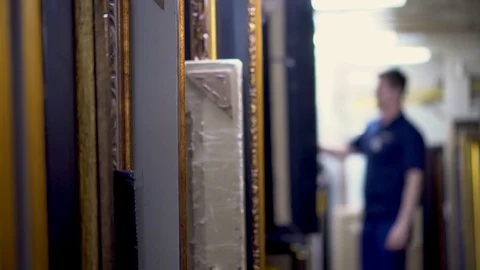 Art frames standing in a row in storage and man on background counting frames Stock Footage 106664306