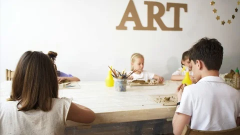 Art lesson in workshop with children and man teaching them to sculpt from clay Stock Footage 109199273