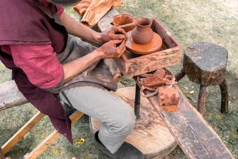 Art of making ceramic ware. Potter finishes work on clay jug. On bench are to Stock Photos