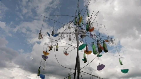 Art object: a wind chime made of bottles in front of blue sky and clouds. Stock Footage 72647263