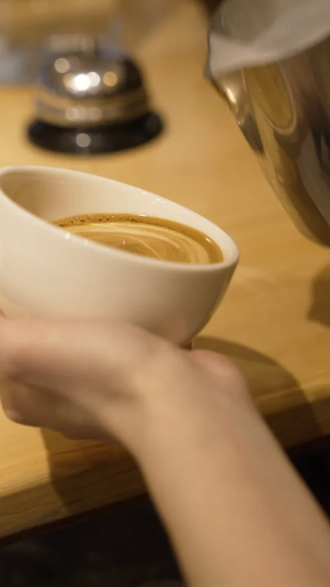 The art of pouring steamed milk into a white coffee cup Stock Footage 315304953