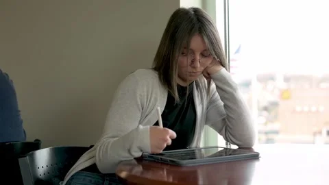 Art student deeply focused on creating digital illustrations with a stylus an Stock Footage 275277457