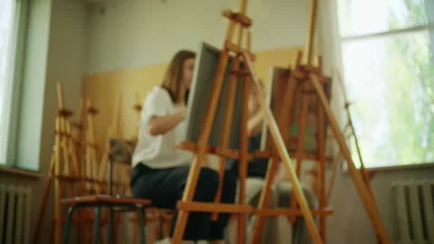 Art students seated at easels practicing drawing techniques during a creative Stock Footage 336899187