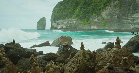 Artfully stacked cairns stand as silent sentinels before the restless ocean Stock Footage 264641633