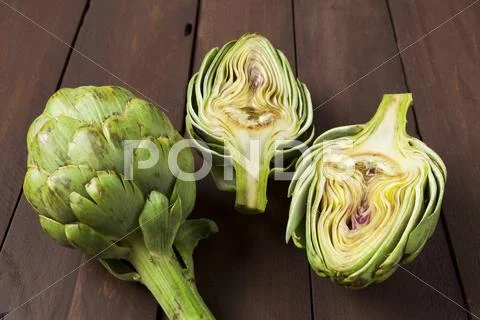 Artichoke cut in half on brown table Stock Photos