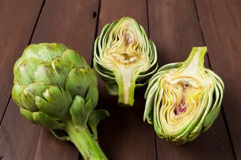 Artichoke cut in half on brown table Stock Photos