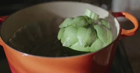 Artichoke steaming in an orange pot with window light shinning in Stock Footage 303872114
