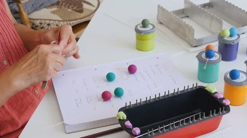 Artiest writes down her ideas for matching bead colors togeather on paper and Stock Footage 77111593