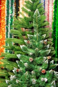 Artificial Christmas pine on a background of multicolored tinsel in blur. Stock Photos