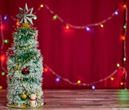 Artificial Christmas tree on a red background with garlands with place for te Stock Photos