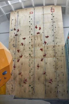 Artificial climbing wall, wooden panel with colourful holds and ropes Stock Photos