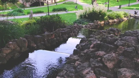 Artificial creek with clean water flows between dark stones Stock Footage 136420604