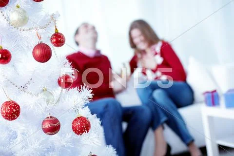 Artificial decorated Christmas tree with a happy couple in the background Stock Photos