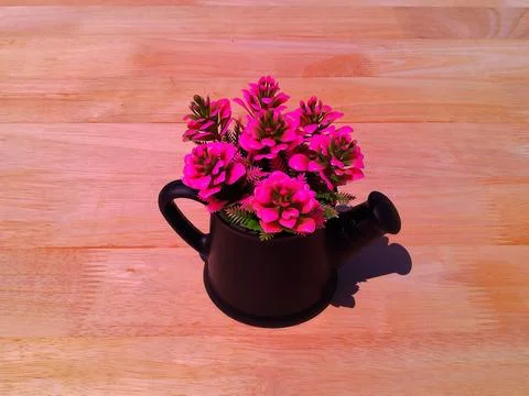 Artificial decorative flowers in a small pitcher-shaped vase Stock Photos