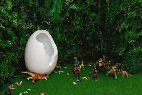 Artificial dinosaur egg on the background of green grass and other greenery a Stock Photos