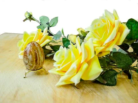 Artificial Easter brown egg and artificial yellow roses Stock Photos