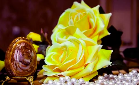 Artificial Easter brown egg and artificial yellow roses Stock Photos