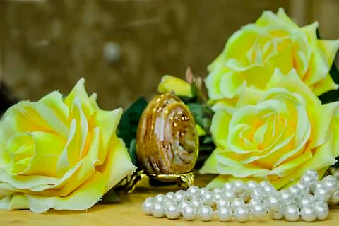 Artificial Easter brown egg and artificial yellow roses Foto stock