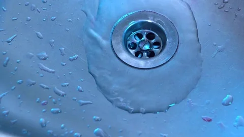 Artificial eyes fall into the sink with a red liquid draining into the drain Stock Footage
