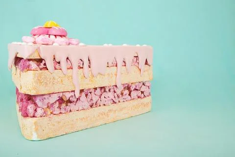 Artificial foam cake slice with pink icing and candy toppings on a vibrant Stock Photos