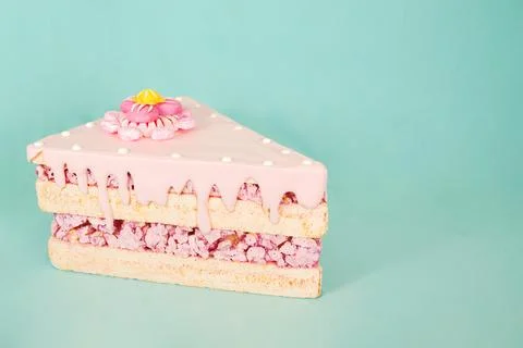 Artificial foam candy cake slice with pink frosting and decorative flower on top Stock Photos