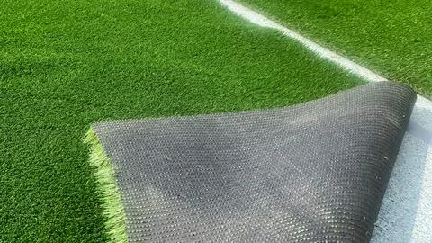 Artificial grass corner folded back, product and installation close-up. Stock Photos