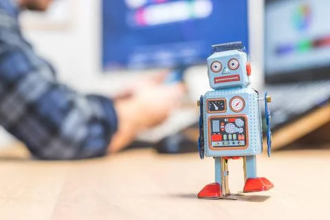 Artificial intelligence concept: Toy robot on office desktop. Metaphor for... Stock Photos