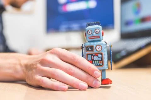Artificial intelligence concept: Toy robot on office desktop. Metaphor for... Stock Photos