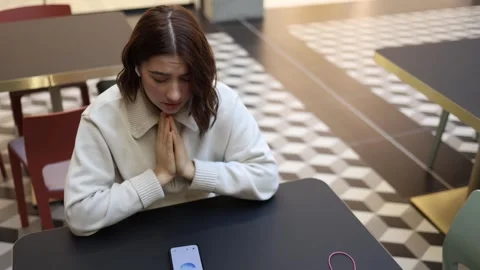 Artificial intelligence joins quiet prayer of young woman in cafe Stock Footage 323738690