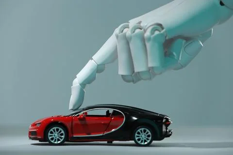 Artificial intelligence. Robot hand with toy car against grey background, c.. Stock Photos