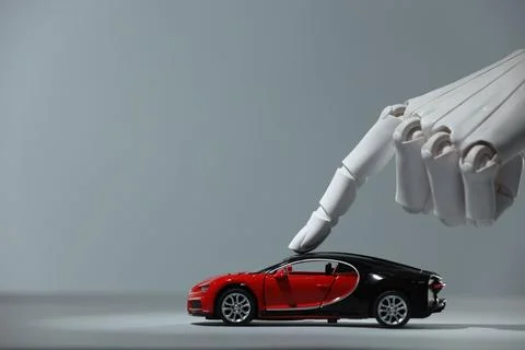 Artificial intelligence. Robot hand with toy car against grey background, c.. Stock Photos