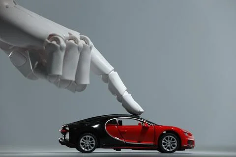 Artificial intelligence. Robot hand with toy car against grey background, c.. Stock Photos