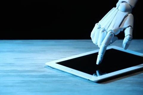 Artificial intelligence. Robot hand using tablet at wooden table, closeup. .. Foto stock