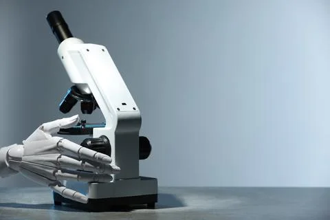 Artificial intelligence. Robot hand working with microscope at table agains.. Foto stock