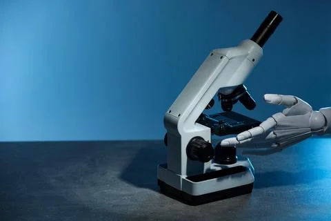 Artificial intelligence. Robot hand working with microscope at grey table a.. Stock Photos
