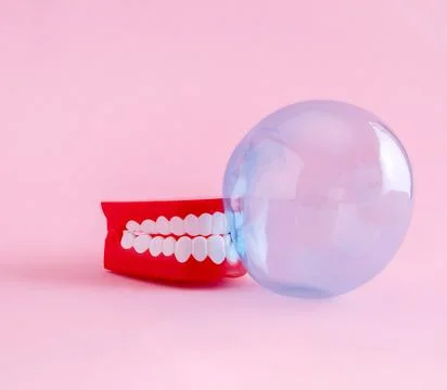 Artificial jaw and bubble of chewing gum on  pink background. Minimal art p.. Stock Photos