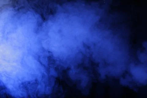 Artificial magic blue light illuminates smoke on dark background Stock Photos