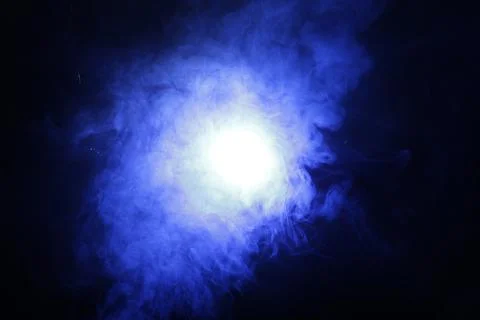 Artificial magic smoke in blue light on black background Foto stock