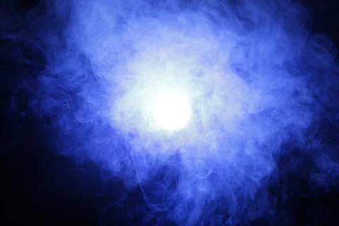 Artificial magic smoke in blue light on black background Stock Photos