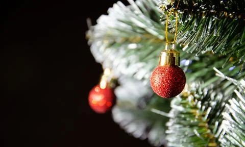 Artificial pine branches in the snow with red Christmas tree balls ornaments. Stock Photos