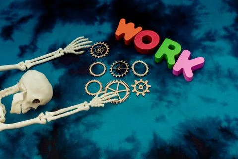 Artificial skeleton, work wording and wooden cogwheels Stock Photos