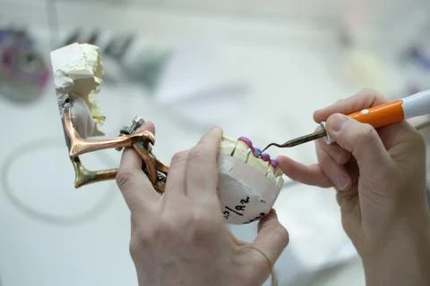 Artificial teeth, prosthetics, hands while working on the denture Stock Photos