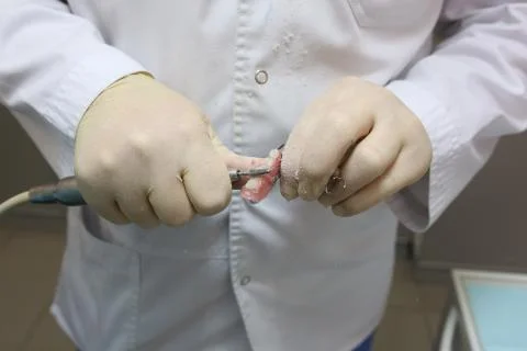Artificial teeth, prosthetics, hands while working on the denture. Stock Photos