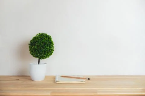 Artificial tree with notebook and pencil on work desk. Stock Photos