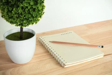 Artificial tree with notebook and pencil on work desk. Stock Photos