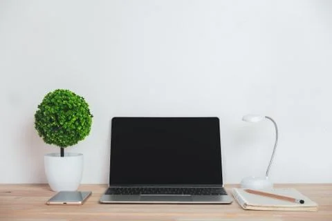 Artificial tree with notebook laptop mobile phone and pencil on work desk. Stock Photos