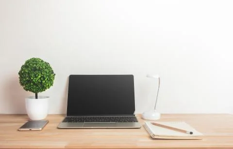 Artificial tree with notebook laptop mobile phone and pencil on work desk. Stock Photos