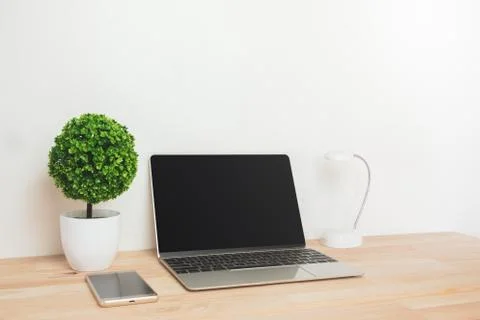 Artificial tree with notebook laptop mobile phone and pencil on work desk. Stock Photos