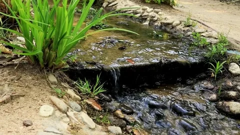 An artificial waterfall cascades and pebble rocks Flowing water in a garden Stock Footage 294198536